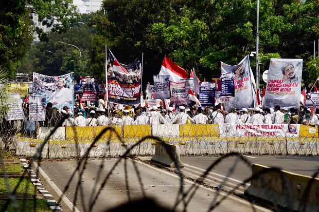 Para pengunjuk rasa membawa poster dan bendera ketika menggelar aksi dekat gedung Mahkamah Konstitusi di Jakarta, saat sidang putusan gugatan Pilpres, 27 Juni 2019. (Arie Firdaus/BeritaBenar)