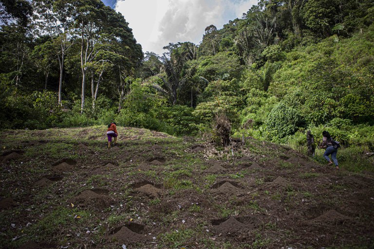 Asmarani Lacege (kiri) dan anaknya (kanan) berjalan dengan susah payah mendaki lereng perkebunan kakao miliknya yang terletak di perbukitan Alitupu, sebuah desa di Kabupaten Poso, Sulawesi Tengah, 19 Maret 2023. [Keisyah Aprilia/BenarNews]