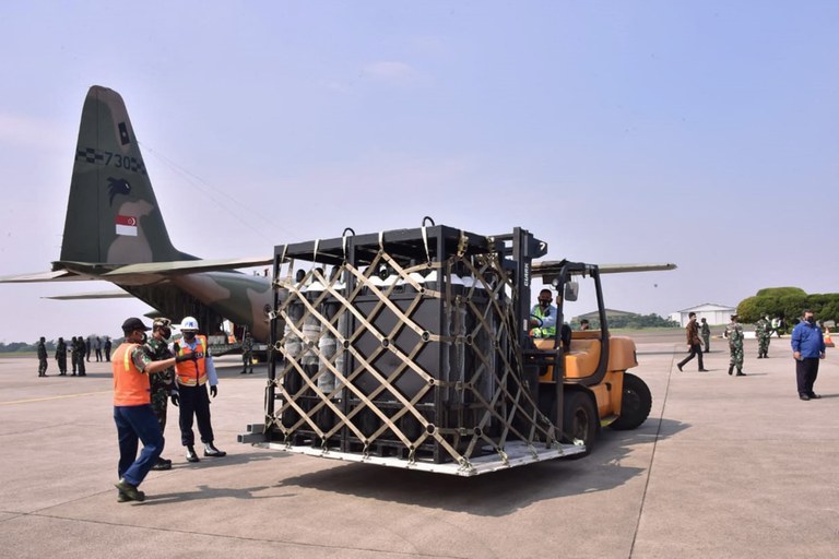 Dalam foto selebaran tertanggal 9 Juli 2021 yang dirilis oleh TNI, petugas mengeluarkan peralatan medis seperti tabung oksigen, ventilators dan lainnya dari pesawat Singapura untuk membantu penanggulangan COVID-19 di pangkalan udara militer Indonesia di Jakarta. [AFP]