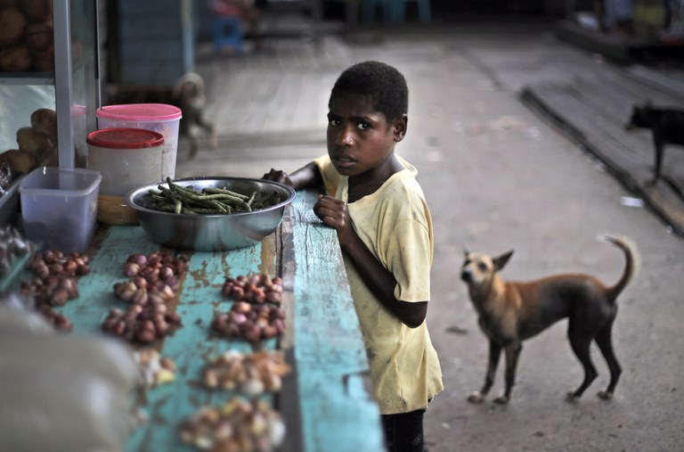 Seorang anak laki-laki berdiri di sebuah warung yang menjual rempah-rempah di sebuah pasar di Wanam, Papua, 16 April 2015. [Dita Alangkara/AP]
