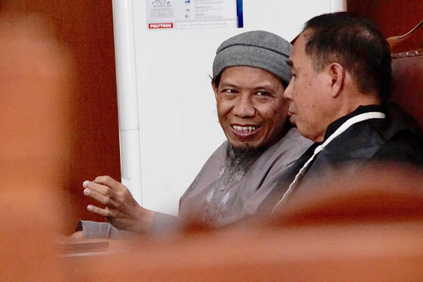 Aman Abdurrahman (kiri) sedang berbincang dengan pengacaranya dalam persidangan di Pengadilan Negeri Jakarta Selatan, 27 April 2018. (Arie Firdaus/BeritaBenar)