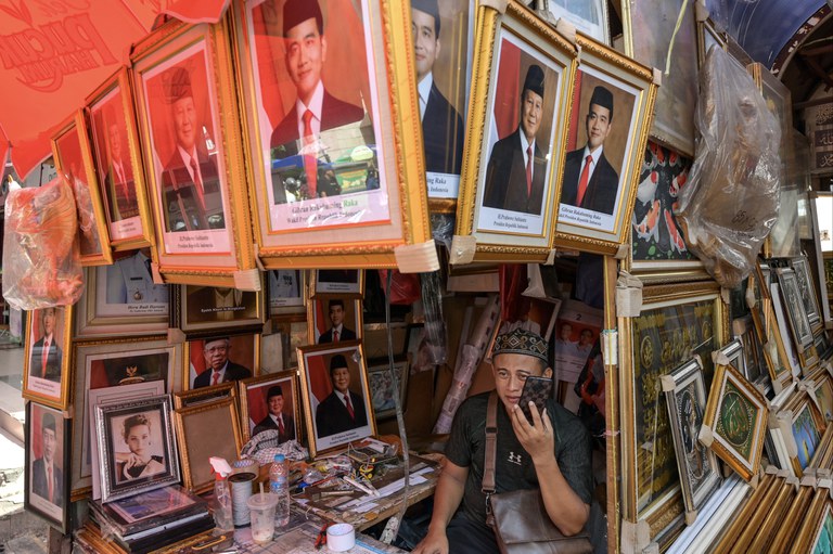 Seorang pedagang menjual foto presiden terpilih Prabowo Subianto (kedua dari kanan) dan wakil presiden terpilih Gibran Rakabuming Raka (tengah) di kiosnya di Jakarta, 23 April 2024. [Bay Ismoyo/AFP]