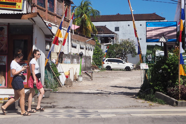 Dua turis melewati lahan bekas Sari Club, di Kuta, Bali, 1 Mei 2019. (Anton Muhajir/BeritaBenar)