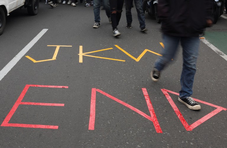 Mahasiswa berjalan melewati tulisan “JKW END” dalam unjuk rasa mengecam dugaan campur tangan Presiden Joko “Jokowi” Widodo dalam Pemilu 2024  di Jakarta, 7 Februari 2024. [Ajeng Dinar Ulfiana/Reuters]