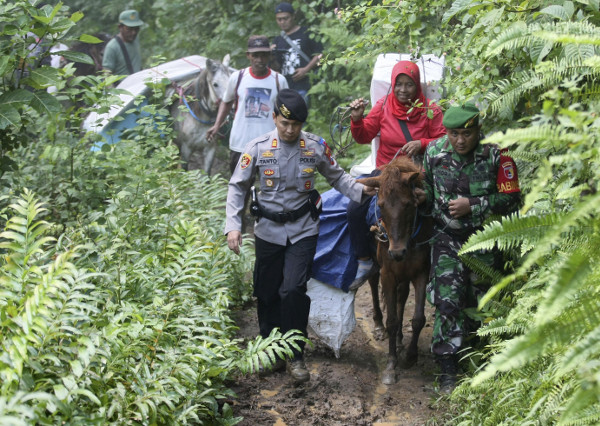 Polisi dan tentara ikut menjaga kotak suara yang diangkut dengan kuda ke TPS-TPS di sejumlah desa di Tempurejo, Jawa Timur, 15 April 2019. (AP) 