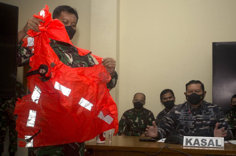 Seorang anggota TNI Angkatan Laut memperlihatkan jaket pengaman yang ditemukan di perairan di sekitar lokasi karamnya kapal selam KRI Nanggala-402, dalam sebuah konferensi pers di Pangkalan TNI AL Ngurah Rai, di Denpasar, Bali, 25 April 2021. [AP]