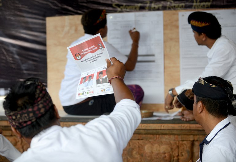 Petugas menghitung surat suara di tempat pemungutan suara setelah berakhirnya waktu pemilihan di Kuta, Bali, 17 April 2019. [Sonny Tumbelaka/AFP]