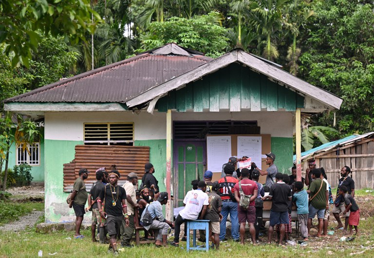 Warga Papua menyaksikan petugas pemilu menghitung surat suara di sebuah TPS di Distrik Kwamki Narama, Kabupaten Mimika, Papua Tengah, pada hari pemilu, 14 Februari 2024. [Adek Berry/AFP]
