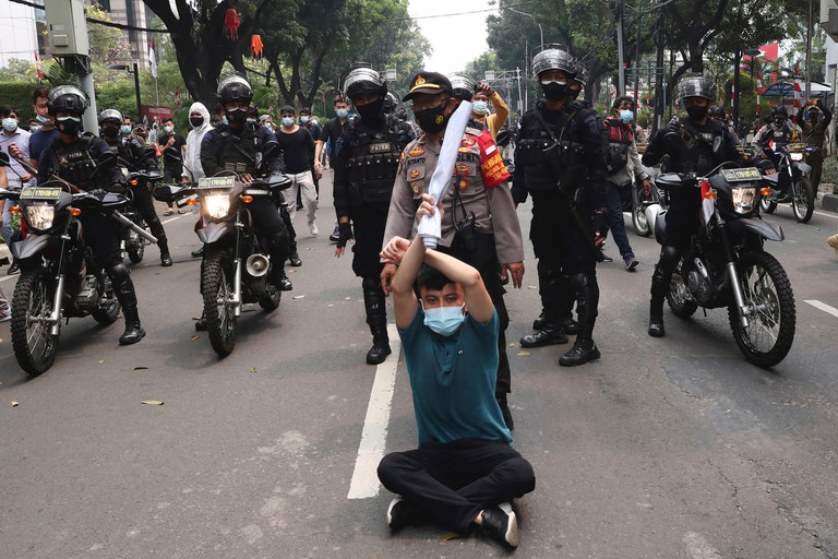 Seorang pengungsi Afghanistan berunjuk rasa di depan petugas polisi dalam demonstrasi di luar gedung kantor perwakilan UNHCR di Jakarta, Selasa, 24 Agustus 2021. [AP]