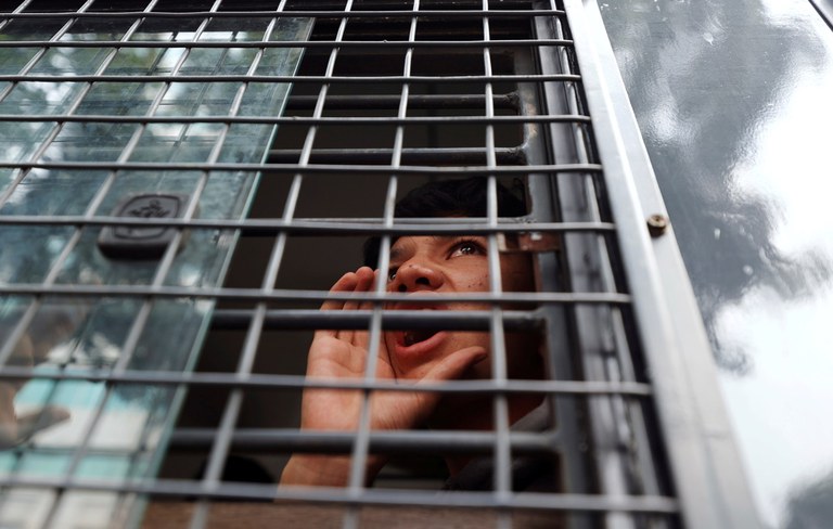 Seorang pengungsi Afghanistan berteriak dari dalam kendaraan polisi saat ia ditahan dalam demonstrasi di luar gedung kantor perwakilan UNHCR di Jakarta, Selasa, 24 Agustus 2021. [Reuters]