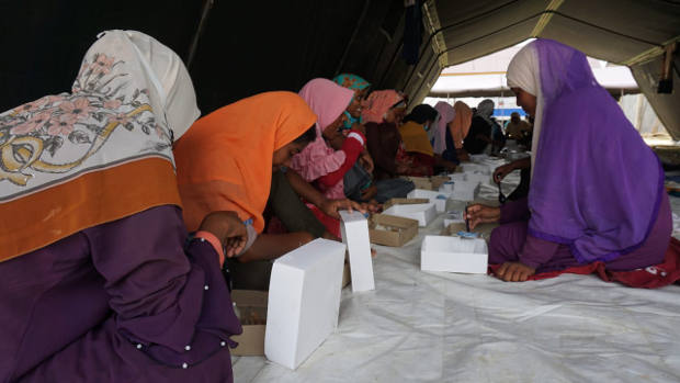 Imigran Rohingnya yang terdampar di Aceh menikmati makanan di dalam tenda yang didirikan di kompleks Balai Latihan Kerja (BLK) Kota Lhokseumawe, Aceh, 8 September 2020. [Muzakir Nurdin/BenarNews]