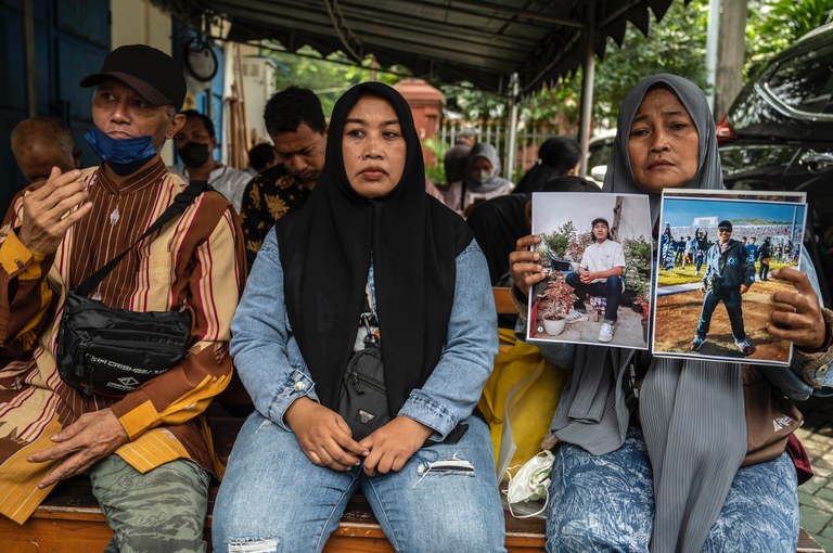 Rini Hanifah (kanan) menunjukkan foto mendiang putranya Agus Riansyah, salah satu dari 135 orang yang tewas dalam bencana stadion sepak bola Kanjuruhan 1 Oktober 2022, saat menghadiri persidangan di Pengadilan Negeri Surabaya pada 16 Januari 2023. [Juni Kriswanto/AFP]