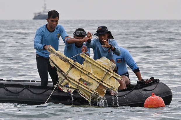 Penyelam TNI AL mengangkat bagian dari bangkai pesawat Sriwijaya Air penerbangan SJ-182 dalam operasi pencarian dan penyelamatan di laut dekat pulau Lancang, Kepulauan Seribu, pada 10 Januari 2021. [AFP]