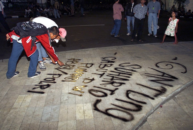 Mahasiswa pengunjuk rasa membuat grafiti bertuliskan "Gantung Suharto, Cabut Dwi Fungsi ABRI/Polri" di dekat kediaman mantan presiden Suharto di Jakarta, 20 Mei 2000, memperingati dua tahun kejatuhannya, dan menuntut agar mantan presiden yang berkuasa selama 32 tahun itu diadili. [Oka Budhi/AFP]