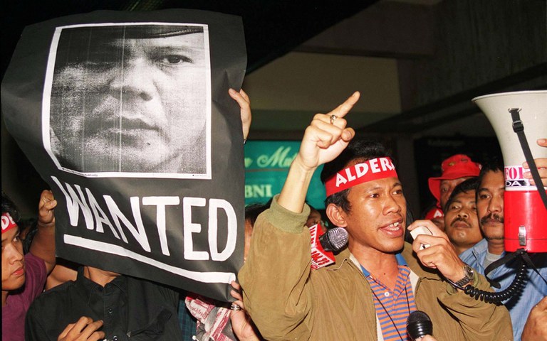 Aktivis mahasiswa Indonesia, Pius Lustrilanang, aktivis pertama yang berbicara secara terbuka tentang penculikan dan penyiksaan yang dilakukan oleh para penculik tak dikenal, memberikan pidato di samping poster Letjen Prabowo Subianto, setibanya di bandara Jakarta, 19 Juli 1998. [Reuters]