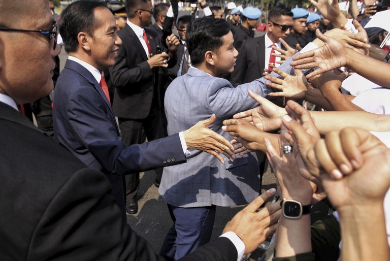 Presiden Joko Widodo dan putranya, Gibran Rakabuming Raka, menyambut para pendukungnya sebelum pelantikan masa jabatan keduanya, di Jakarta, 20 Oktober 2019. [AP]