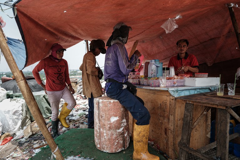 Foto yang diambil pada 14 September 2023 ini menunjukkan para pemulung yang mengumpulkan sampah plastik untuk dijual, beristirahat di sebuah warung kopi di lingkungan tempat pembuangan sampah di Bantar Gebang, Bekasi, Jawa Barat. [Yasuyoshi Chiba/AFP]