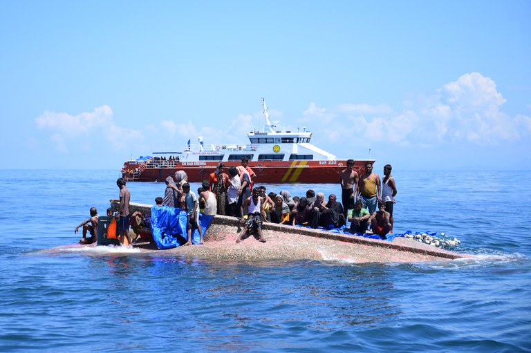 Pengungsi Rohingya menunggu untuk diselamatkan dari lambung kapal mereka yang terbalik ketika kapal Badan Pencarian dan Pertolongan Nasional (Basarnas) mendekat di perairan sekitar 29 kilometer lepas pantai barat Aceh pada 21 Maret 2024. [Zahlul Akbar/AFP]