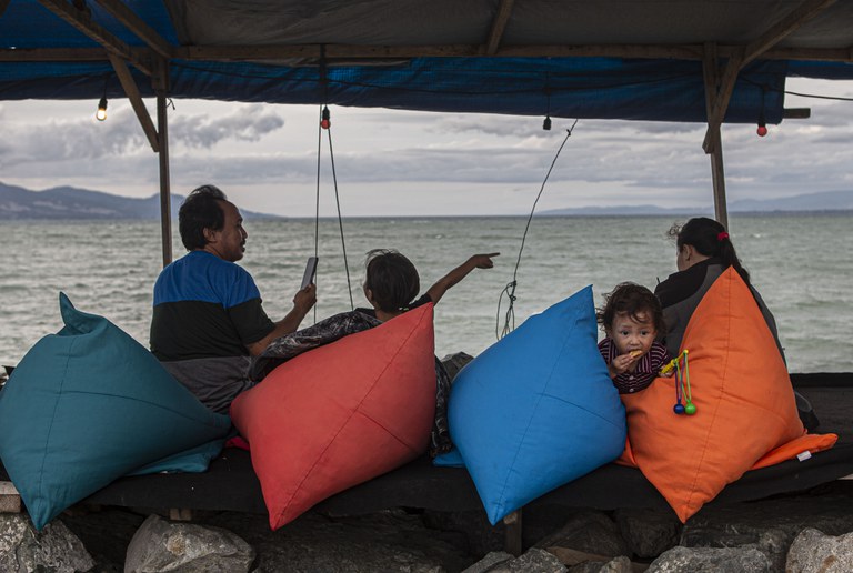 Sebuah keluarga bersantai dengan pemandangan laut di salah satu kafe yang dibangun di atas tanggul Teluk Palu di Pantai Talise, Palu, Sulawesi Tengah, Rabu, 15 Februari 2023. Kafe-kafe ini mulai beroperasi sejak sore pukul 15.00 WITA hingga tutup pukul 00.00 WITA setiap harinya. Menurut sejumlah penyintas, dengan kembali berjualan di lokasi ini, mereka merasa senang karena bisa mendapatkan penghasilan untuk menghidupi keluarga pasca musibah dahsyat 28 September 2018. Sebelum akhirnya bisa kembali beraktivitas di lokasi ini, penyintas bingung dan tidak tahu mau bekerja apa, sementara sebelum benca alam terjadi, mayoritas mereka adalah pedagang di kafe-kafe sepanjang pesisir Teluk Palu. [Taufan Bustan/BenarNews]