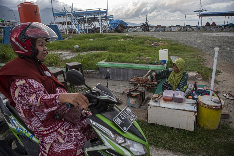 Seorang penyintas gempa bumi dan tsunami membuat makanan khas Pulau Sulawesi, jepa, dengan alat tradisional yang dipesan oleh pengunjung di depan tanggul Teluk Palu di Pantai Talise, Rabu, 15 Februari 2023. Pedagang yang mayoritas ibu-ibu paruh baya itu bersemangat kembali berjualan setelah sempat berhenti sejak 2018 hingga 2021. Mereka istirahat selain karena bencana alam, juga karena pandemi Covid-19. [Taufan Bustan/BenarNews]