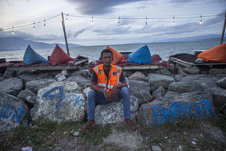Seorang penyintas gempa bumi dan tsunami, M. Rahman duduk di atas tanggul Teluk Palu di Pantai Talise, Palu, Sulawesi Tengah, Rabu, 15 Februari 2023. Pria 35 tahun ini akhirnya bisa bekerja lagi meski hanya sebagai juru parkir di kawasan itu. Rahman yang dulunya nelayan, trauma kembali melaut pascabencana alam 28 September 2018 itu. Kini, ia bisa lebih tenang bekerja dan mendapatkan penghasilan meski hanya sebagai seorang juru parkir yang tidak takut beraktivitas di seputaran zona merah. [Taufan Bustan/BenarNews]