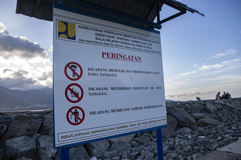 Papan peringatan yang dipasang pemerintah di depan tanggul Teluk Palu, Pantai Penggaraman, Palu, Sulawesi Tengah, Sabtu, 18 Februari 2023. Dalam papan ini, salah satu peringatannya adalah larangan mendirikan bangunan di atas tanggul. Meskipun ada papan peringatan, namun faktanya warga yang merupakan penyintas bencana alam Palu, dikecualikan. Mereka diperbolehkan membangun tempat usaha seperti kafe di atas tanggul, asal sifatnya tidak merupakan bangunan permanen. [Taufan Bustan/BenarNews]