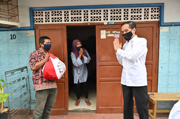 Presiden Joko Widodo mengucapkan salam setelah memberikan paket sembako ke warga yang terdampak pandemi COVID-19 di Jakarta, 18 Mei 2020. [AFP]