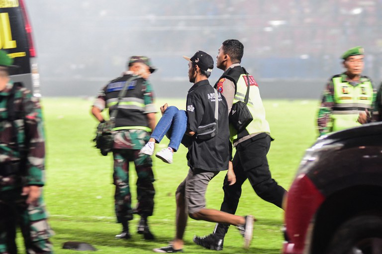 Seorang korban terluka tampak dilarikan ke tempat yang aman dalam kerusuhan yang terjadi setelah polisi menembakkan gas air mata untuk mengusir ribuan supporter Arema FC Malang yang turun ke lapangan setelah tim tuan rumah kalah dari Tim Persebaya Surabaya di Stadion Kanjuruhan Malang, Jawa Timur, 1 Oktober 2022. [AFP]