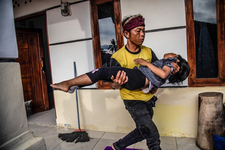 Seorang warga membawa anaknya yang terluka menyusul gempa berkekuatan 5,6 yang menimpa Cianjur dan menewaskan sedikitnya 260 orang, 22 November 2022. [Aditya Aji/AFP]