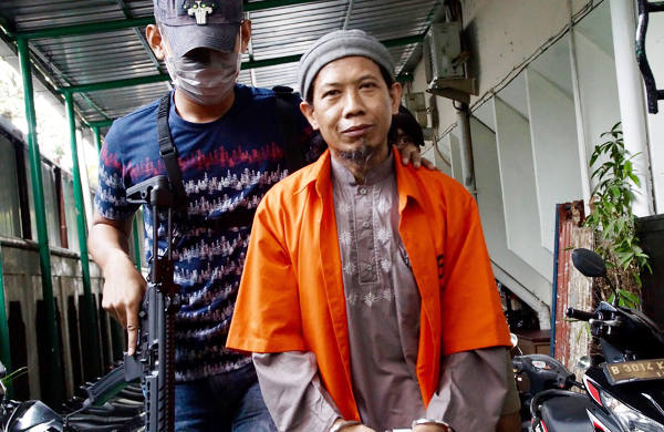 Terdakwa kasus terorisme Aman Abdurrahman dikawal aparat bersenjata memasuki Pengadilan Negeri Jakarta Selatan, 6 Maret 2018. (Arie Firdaus/BeritaBenar)