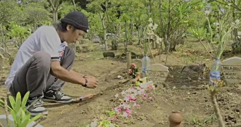 Devi Athok Yulfitri berdoa di makam kedua putrinya dan ibu mereka yang menjadi korban tragedi di Stadioni Kanjuruhan pada 1 Oktober lalu di Pemakaman Umum Desa Sukolilo di Malang, Jawa Timur, 17 Januari 2023. [Eko Widianto/BenarNews]