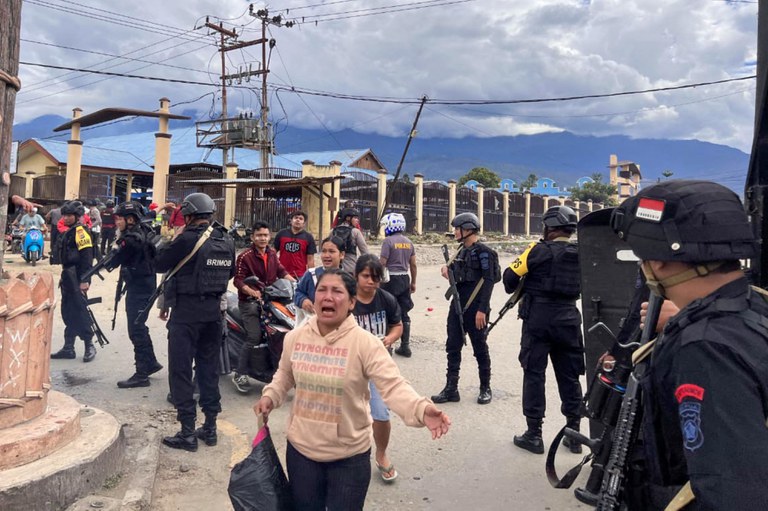 Foto yang diambil pada 23 Februari 2023 ini menunjukkan petugas polisi mengawal warga sipil di Wamena, dalam kerusuhan yang mengakibatkan 12 orang tewas, yang menurut polisi dipicu oleh desas-desus penculikan anak. [Aciz Razi/AFP]