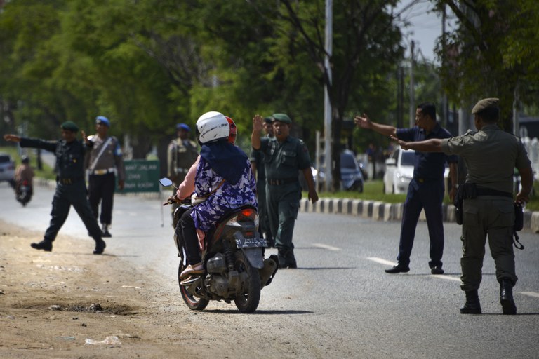 Anggota polisi Syariah menghentikan pengendara untuk pemeriksaan pakaian warga agar sesuai dengan aturan Syariah Islam di sepanjang jalan di Lambaro, Provinsi Aceh, 23 Juli 2019. [Chaideer Mahyuddin/AFP]