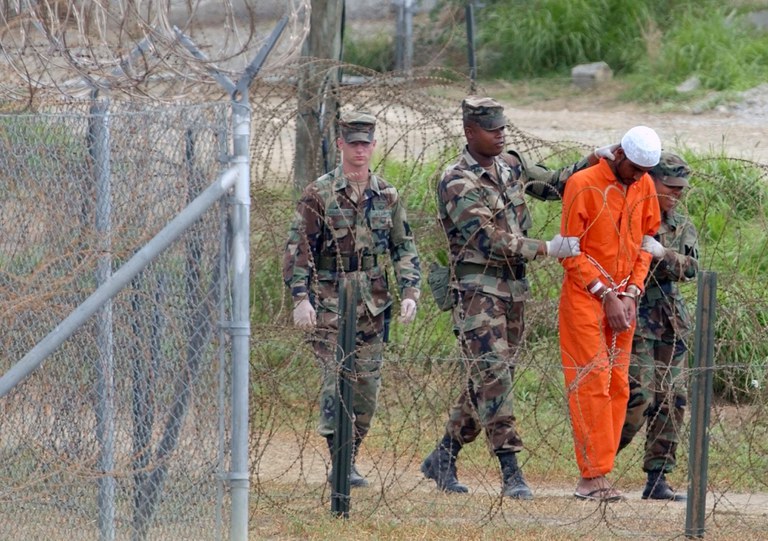 Polisi militer menggiring seorang tahanan untuk diinterogasi di Kamp X-Ray, di Pangkalan Angkatan Laut AS Teluk Guantanamo, Kuba, 6 Februari 2002. [Lynne Sladky/Foto arsip AP]