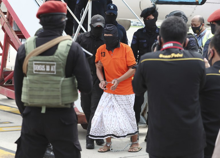 Polisi mengawal tersangka salah satu pimpinan jaringan Jemaah Islamiyah, Zulkarnaen (tengah), yang juga dikenal sebagai Aris Sumarsono, setibanya di Bandara Internasional Soekarno-Hatta di Tangerang, Banten, 16 Desember 2020. [AP]