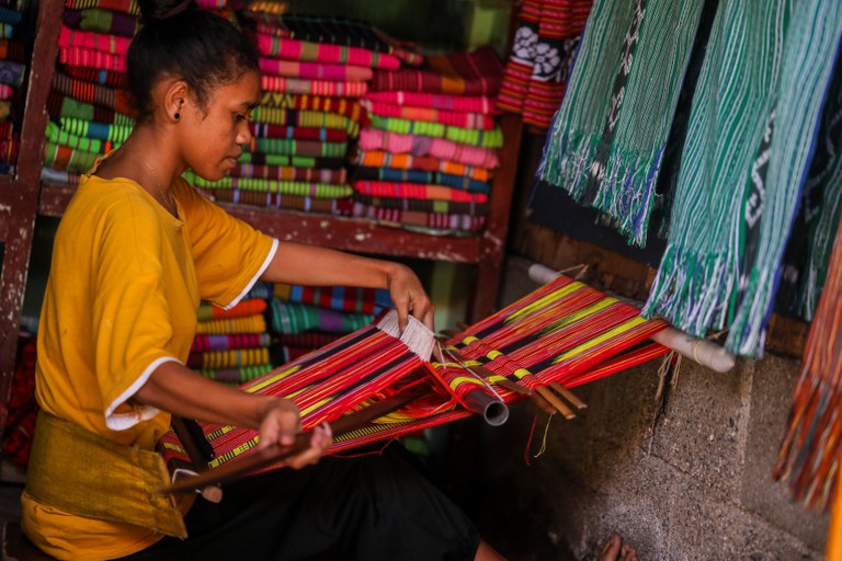 Natalina da Costa, seorang siswa sekolah menengah di Dili, menenun “tais” kain tradisional Timor di Pasar Tais di Colmera, Dili, pada 7 Juli 2023. [Julião Fernandes Guterres/BenarNews]