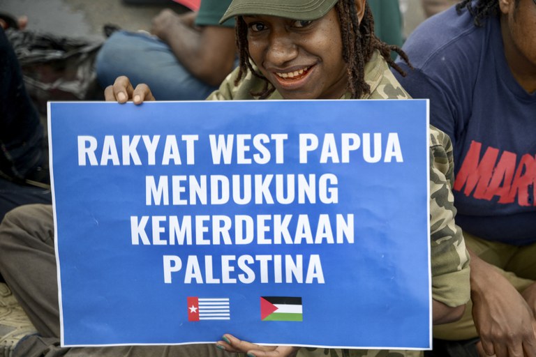 Seorang warga Papua memegang poster bertuliskan dukungan kemerdekaan pada Palestina dalam demonstrasi menuntut referendum kemerdekaan Papua dari Indonesia, di Jakarta, 1 Desember 2023. [Bay Ismoyo/AFP]