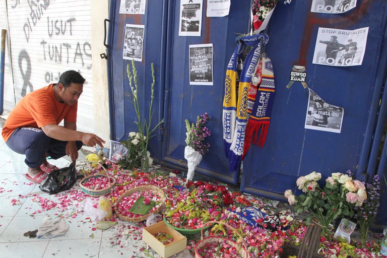 Seorang warga menabur bunga di gerbang 13 Stadion Kanjuruhan untuk mengenang para korban yang tewas dalam kerusuhan sepak bola di Malang, Jawa Timur, 4 Oktober 2022. [Ari Bowo Sucipto/Antara Foto via Reuters]