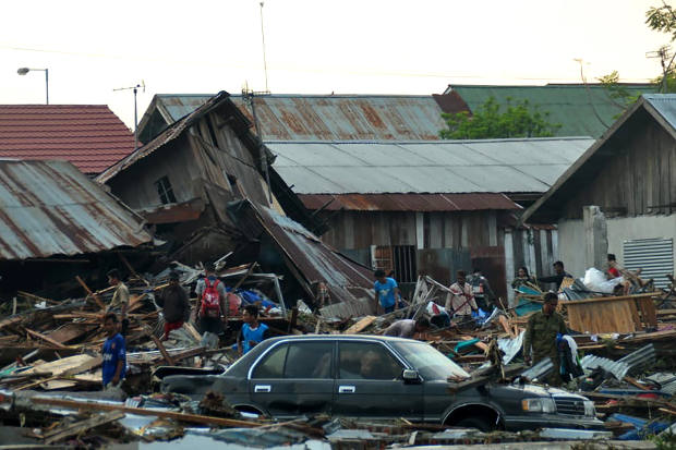 Warga di kota Palu, Sulawesi Tengah, berusaha mencari barang-barang mereka yang bisa diselamatkan di tengah puing-puing akibat gempa yang memicu tsunami melanda wilayah tersebut, 29 September 2018. (AFP)
