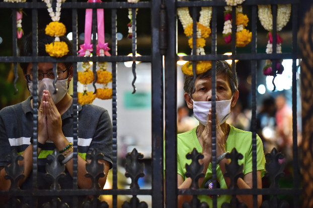 ชาวพุทธไหว้สักการะสิ่งศักดิ์สิทธิ์ ในวันวิสาขบูชา อยู่ภายนอกประตูวัดบวรนิเวศวิหาร เนื่องจากวัดทั่วประเทศปิดงดจัดกิจกรรมทางศาสนา เพื่อไม่ให้ประชาชนรวมตัวกันห้วงสถานการณ์วิกฤตโควิด-19 ในกรุงเทพฯ วันที่ 6 พฤษภาคม 2563 (เอเอฟพี)