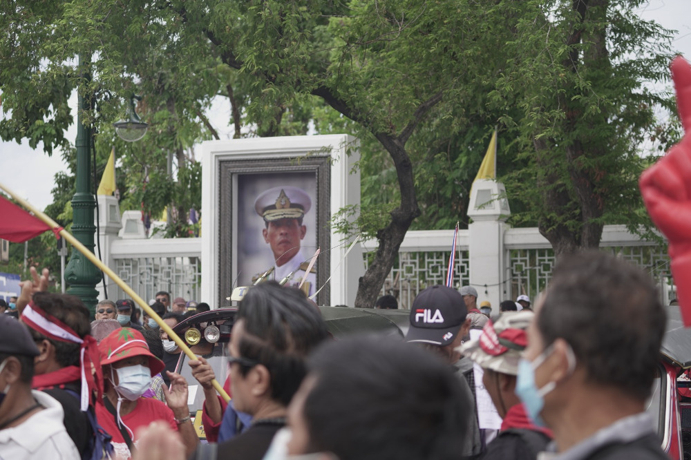 ผู้ประท้วงต่อต้านรัฐบาลเดินผ่านพระบรมฉายาลักษณ์ของพระบาทสมเด็จพระวชิรเกล้าเจ้าอยู่หัว ในกรุงเทพฯ วันที่ 19 กันยายน 2563 (นนทรัฐ ไผ่เจริญ/เบนาร์นิวส์)